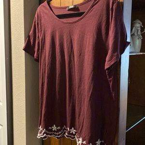 burgundy blouse with white embroidery around the bottom hemline